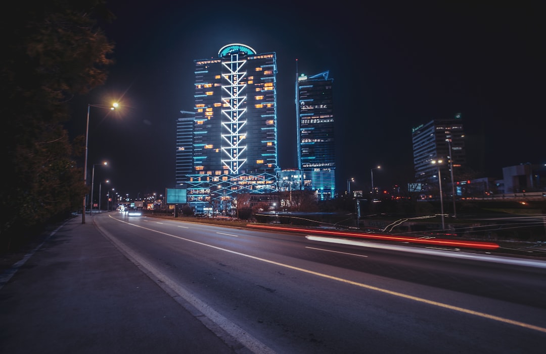 a city street at night with a very tall building in the background