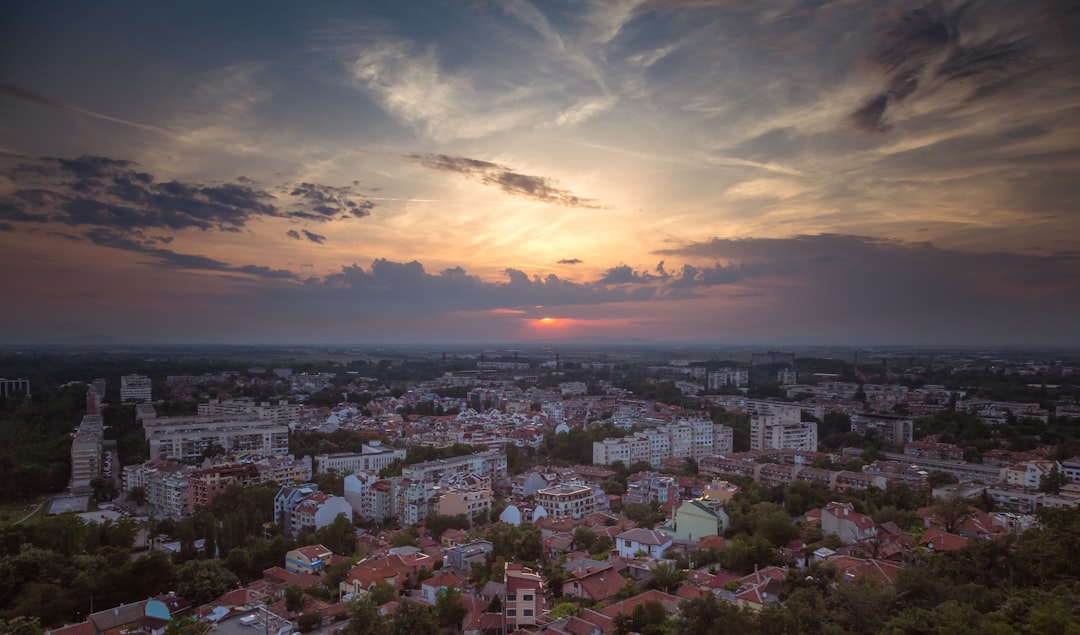 the sun is setting over a city with tall buildings