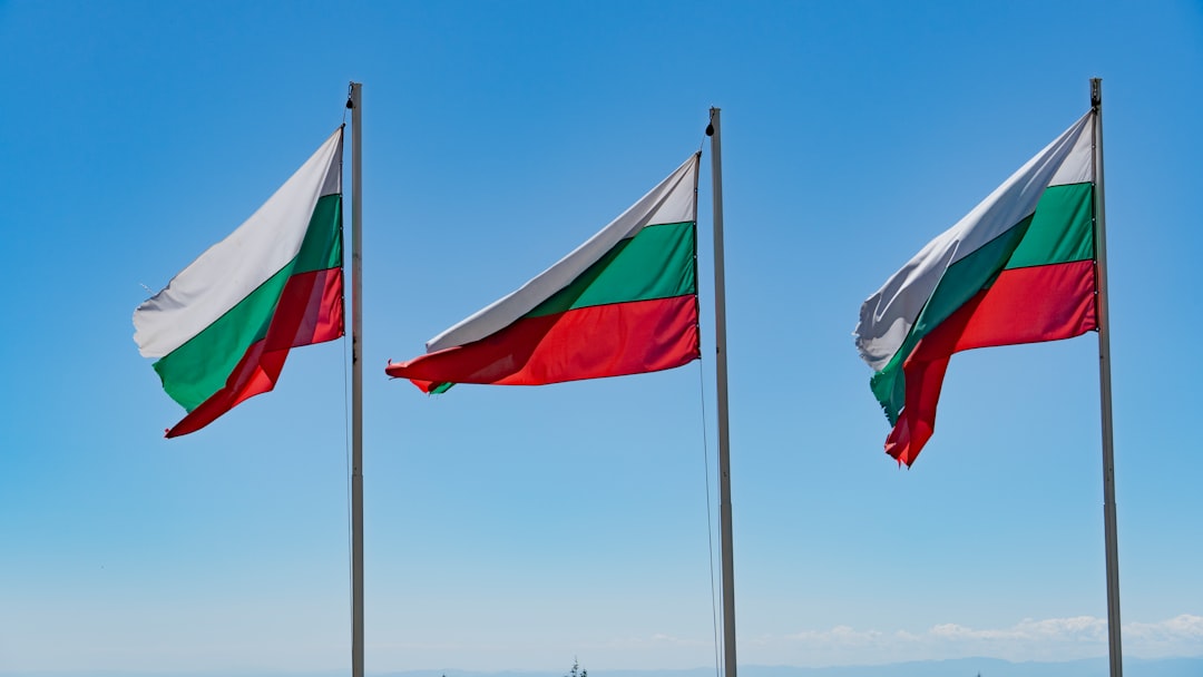 three flags flying in the wind on a sunny day